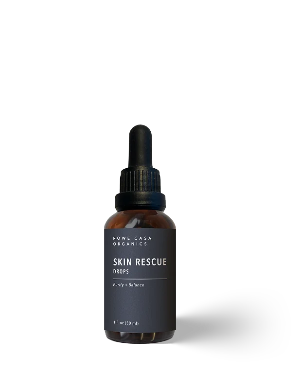 A 1 fl oz amber glass dropper bottle of Rowe Casa Organics Skin Rescue Drops, featuring a dark charcoal label and black dropper cap, set against a clean white background with a soft shadow.