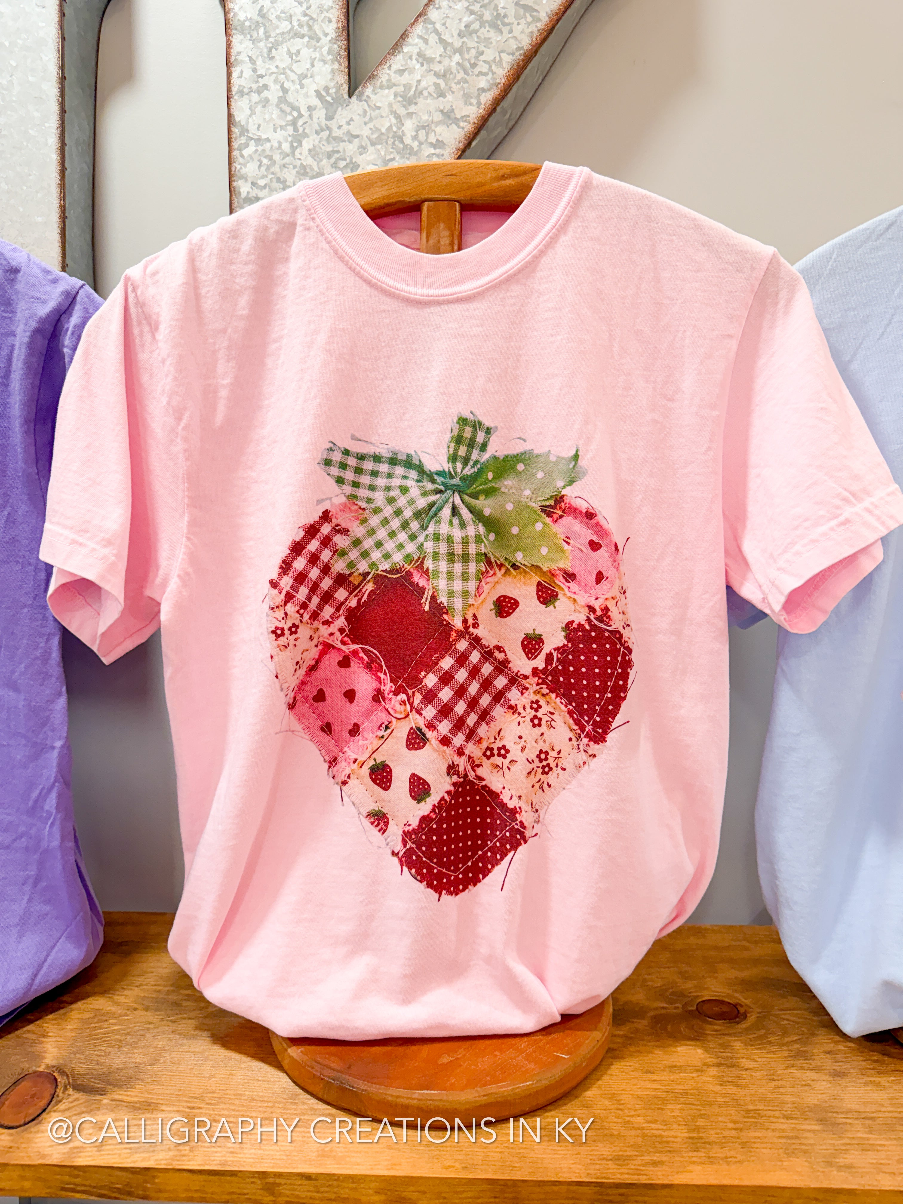 Pink t-shirt with a strawberry design on a wooden surface