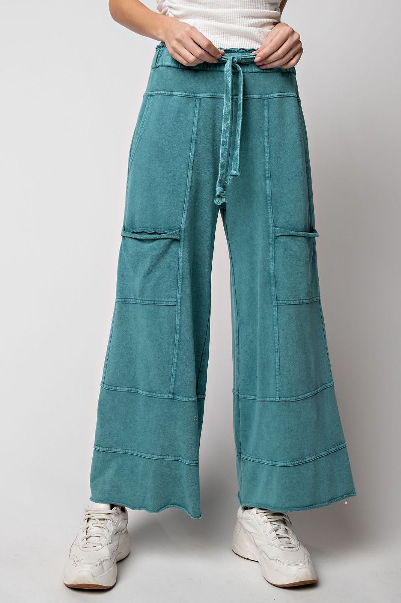 A pair of teal green mineral washed terry knit pants with pockets and elastic ruched waist, displayed on a model.