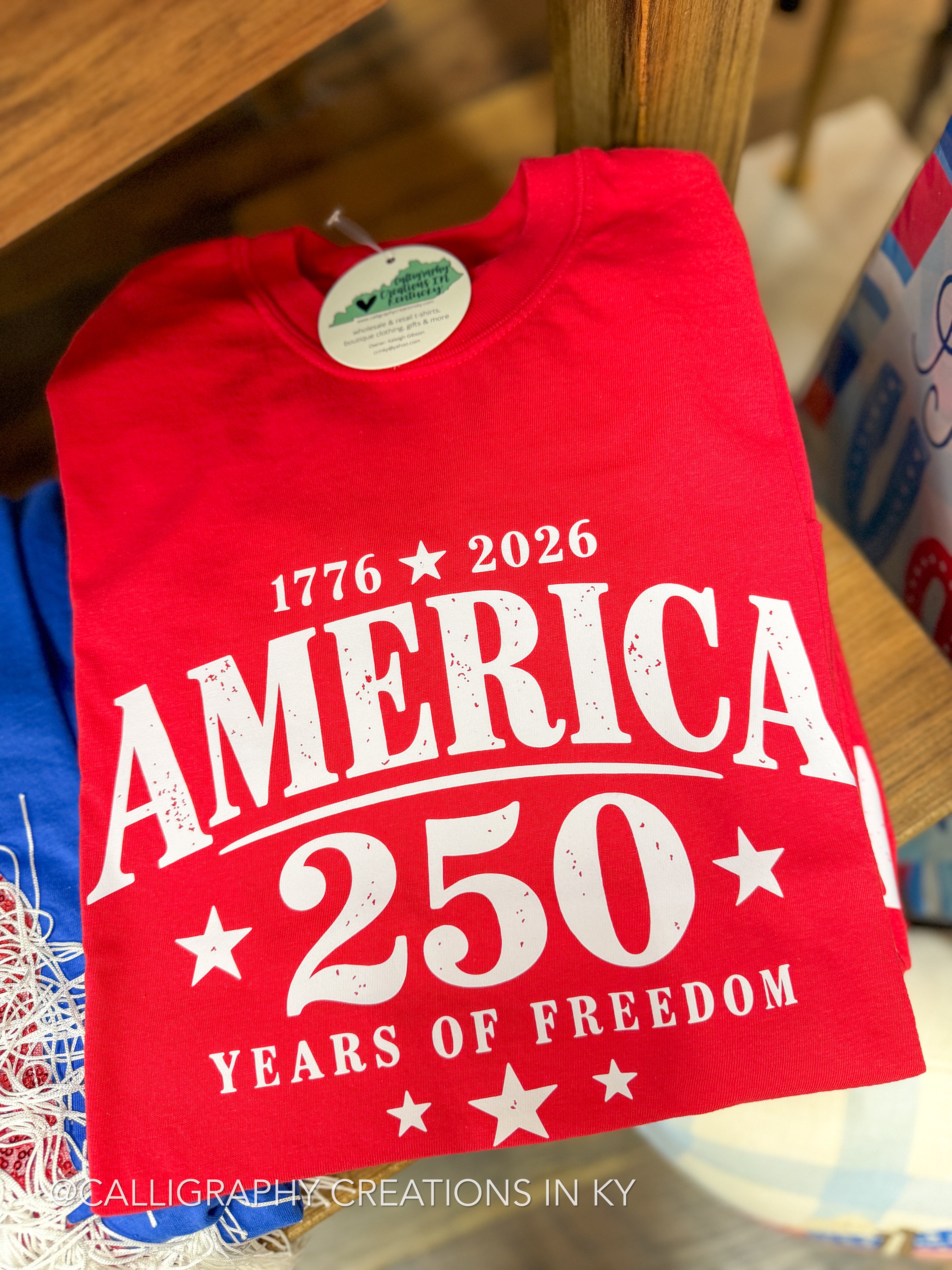 Red t-shirt with 'America 250 Years of Freedom' text on a wooden surface