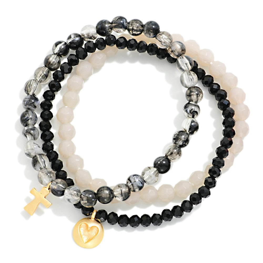Set of beaded bracelets with gold charms on a white background