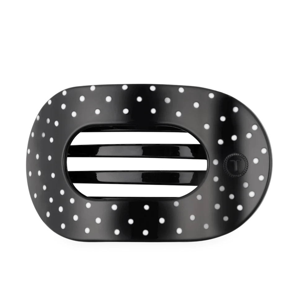 A glossy black oval hair tie with a white polka dot pattern and a central horizontal slit, shown on a plain white background.