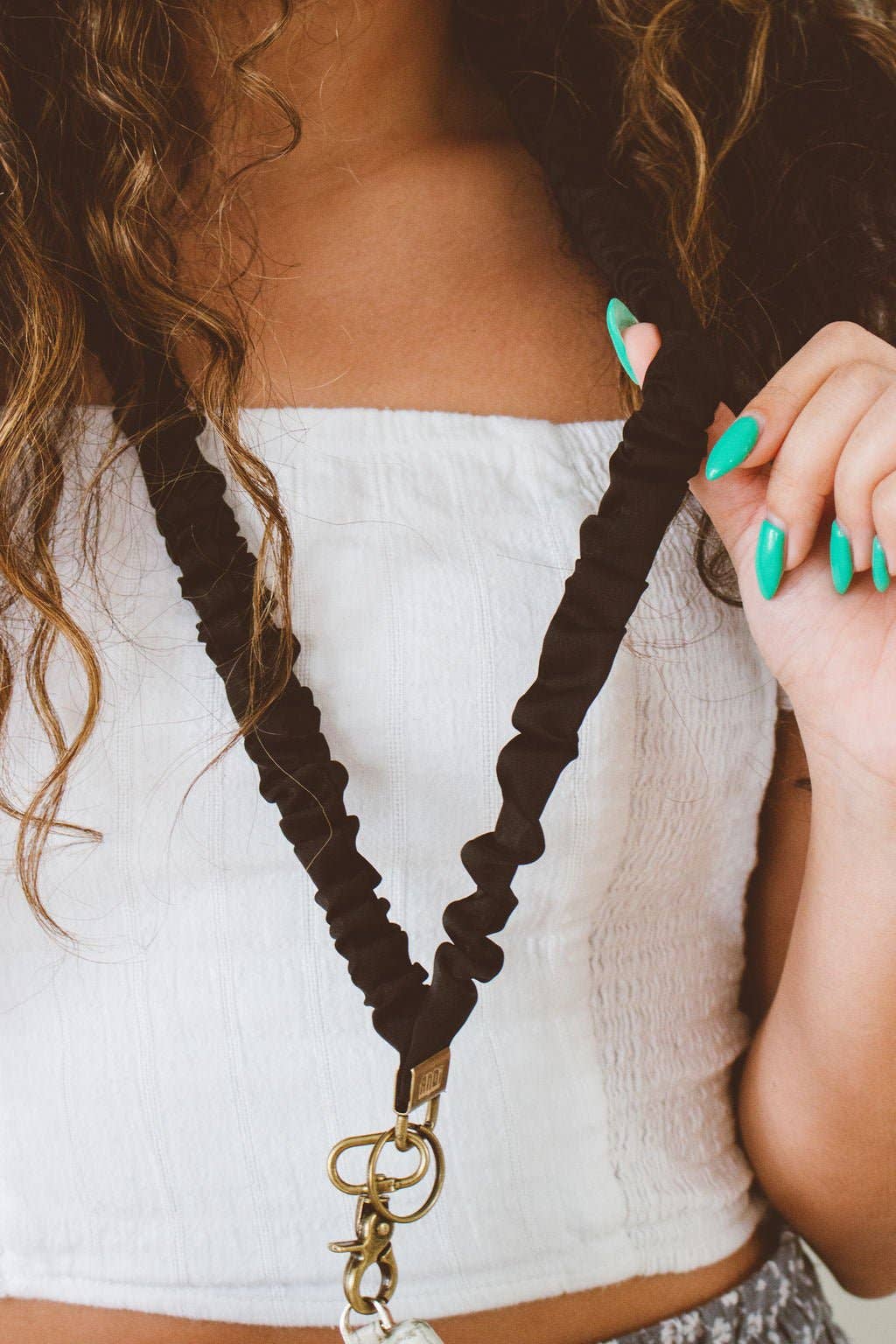 Person wearing a white top with a black scrunchie lanyard around their neck.