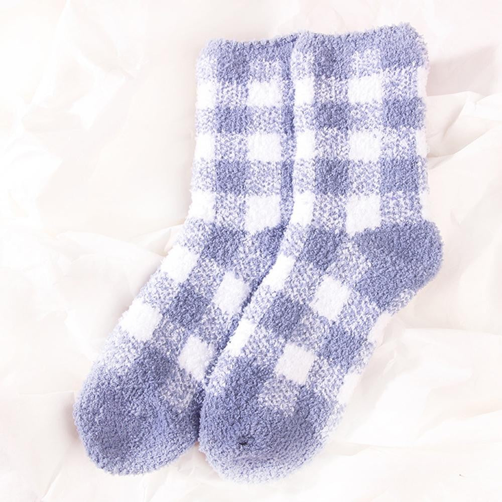 A pair of fuzzy crew socks in a blue and white gingham check pattern, laid flat on a white textured fabric background.