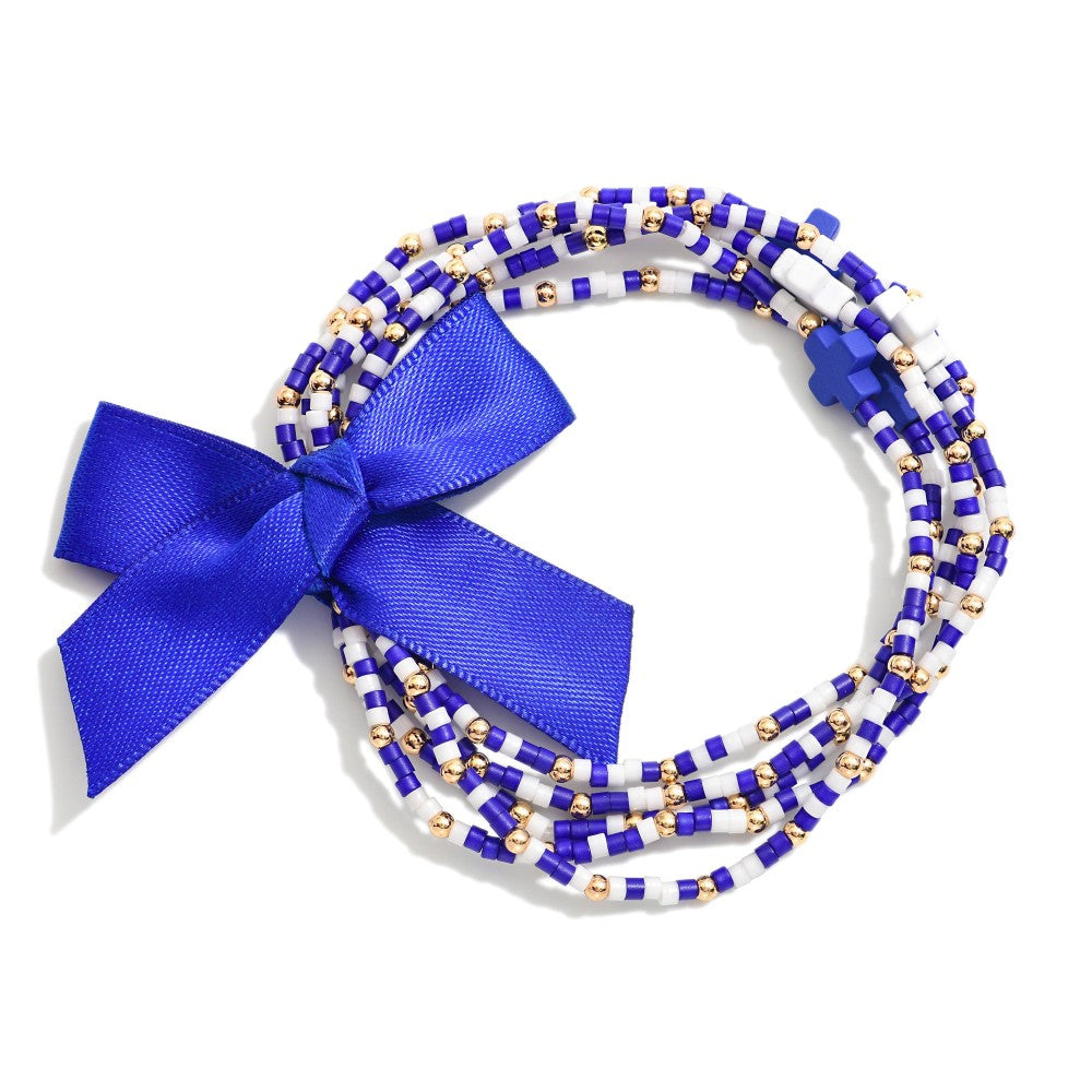 Blue and white bracelet set with gold beads and a bow tied around the bracelets on a white background
