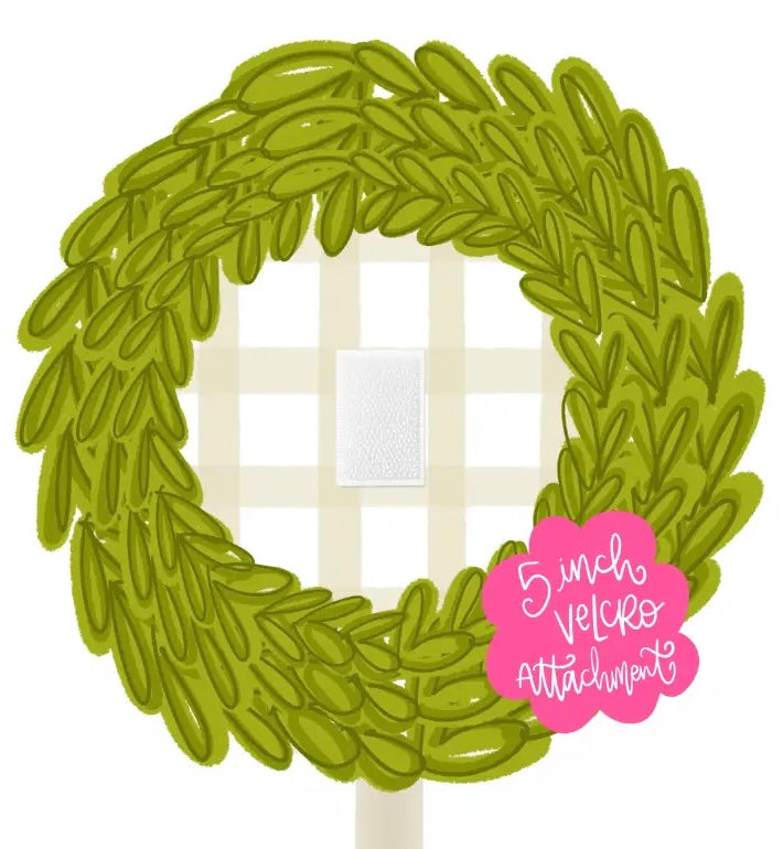 A circular green leafy wreath-shaped applique topper on a white background, with a pink cloud label reading '5 inch velcro attachment' and a small white gingham insert visible in the center.