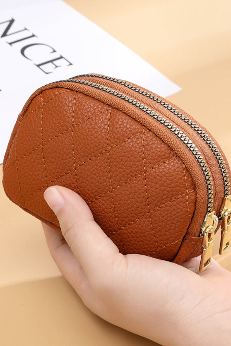 Brown coin purse with gold double zippers in a hand against a wood background