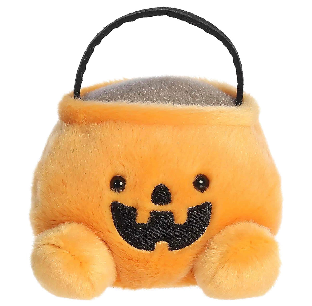 A plush pumpkin-shaped candy bucket with a black handle, featuring embroidered black eyes and a wide black smile on a soft orange-yellow background.