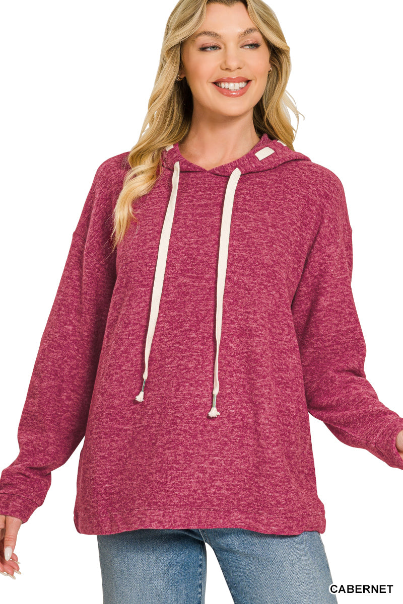 Woman wearing burgundy hoodie with jeans on a white background