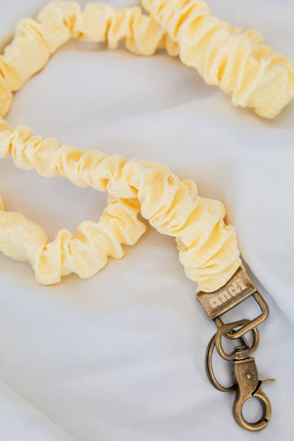 Yellow scrunchie strap with a metal clasp on a white background