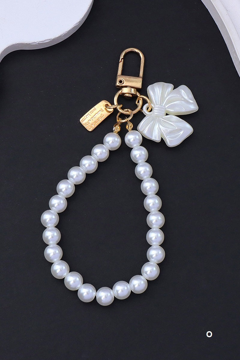 Pearl keychain with white bow and gold clasps on a black background