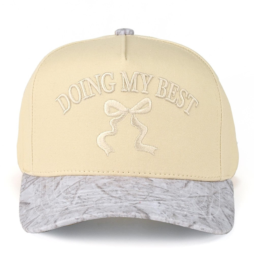 Beige cap with 'Doing My Best' text and bow design on a white background