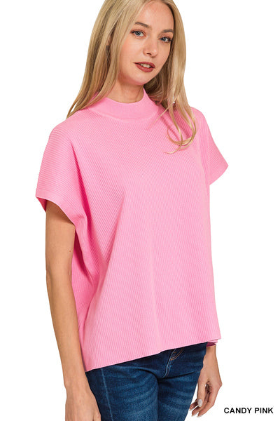 A woman wearing a bright pink ribbed short-sleeve mock neck top and blue jeans, shown against a plain white background with the text 'CANDY PINK' in the bottom right corner.