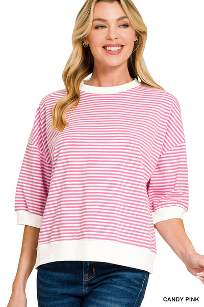 Woman wearing a pink and white striped sweater with blue jeans on a white background