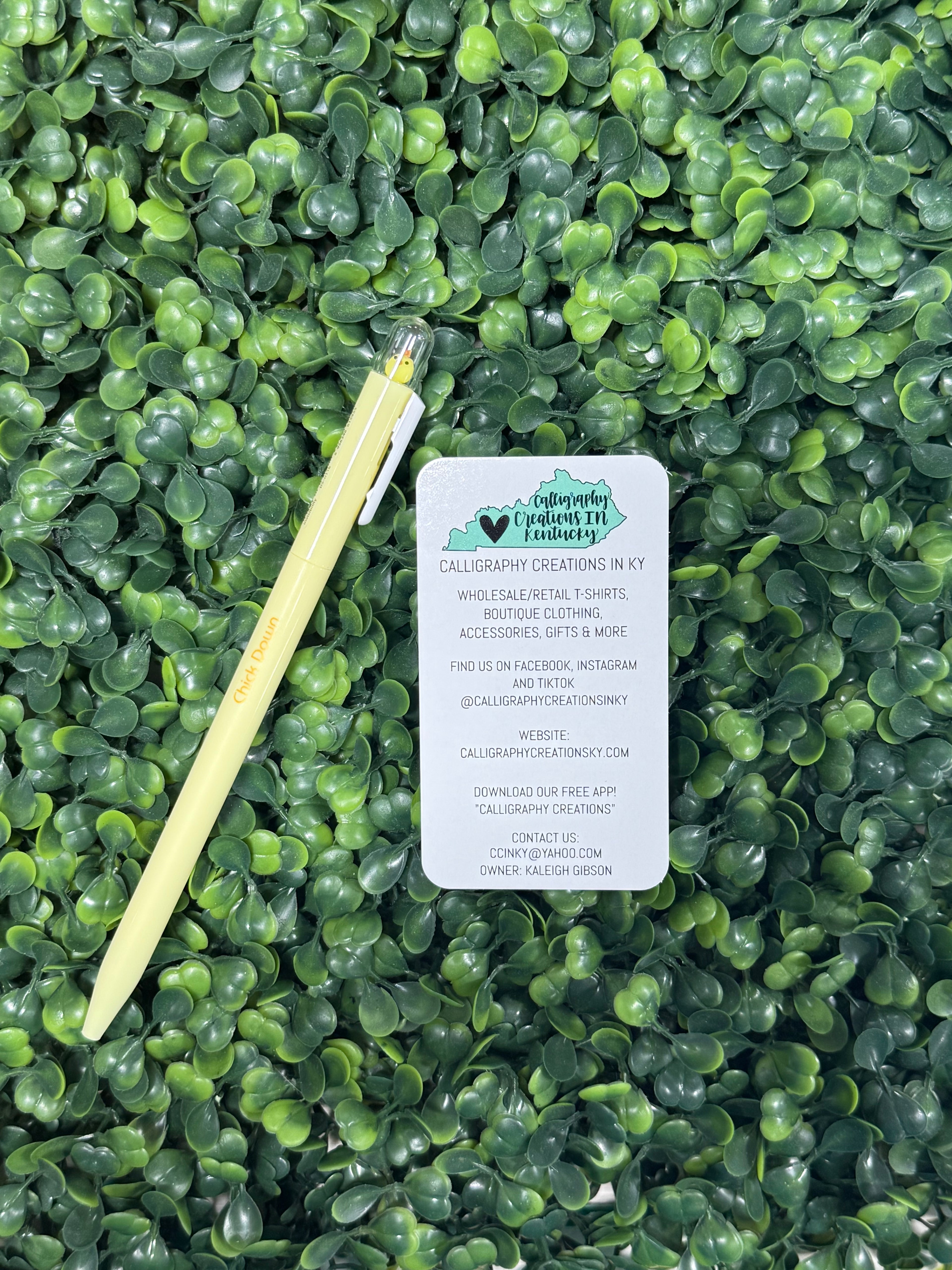 Yellow pen with chick on top on faux greenery background 