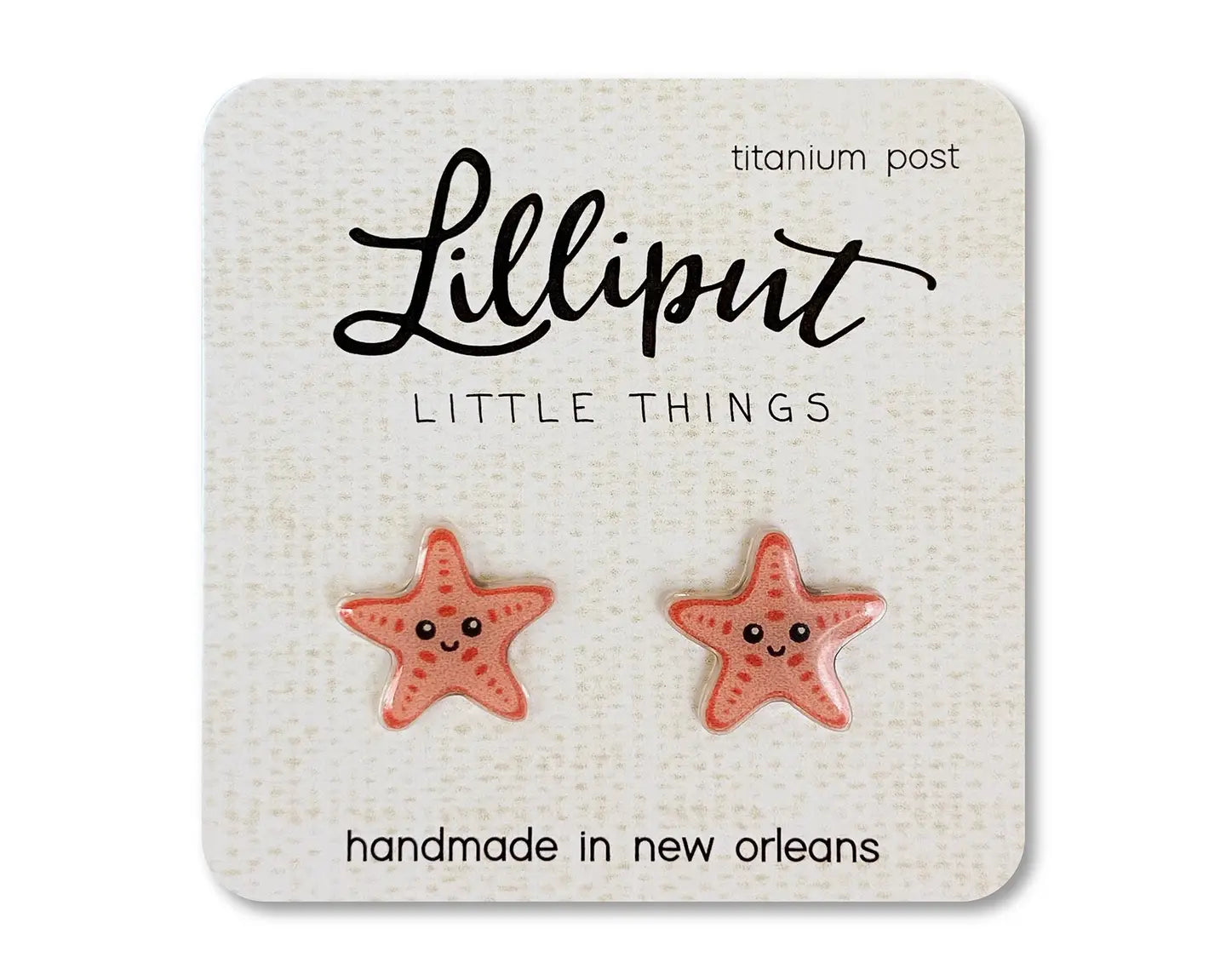 Coral starfish earrings on beige card on white background 