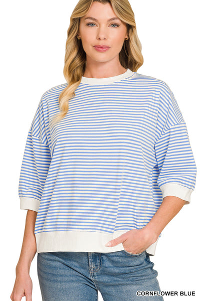 A woman wearing a blue and white striped crewneck sweatshirt with white ribbed trim on the collar, cuffs, and hem, paired with blue jeans against a plain white background.