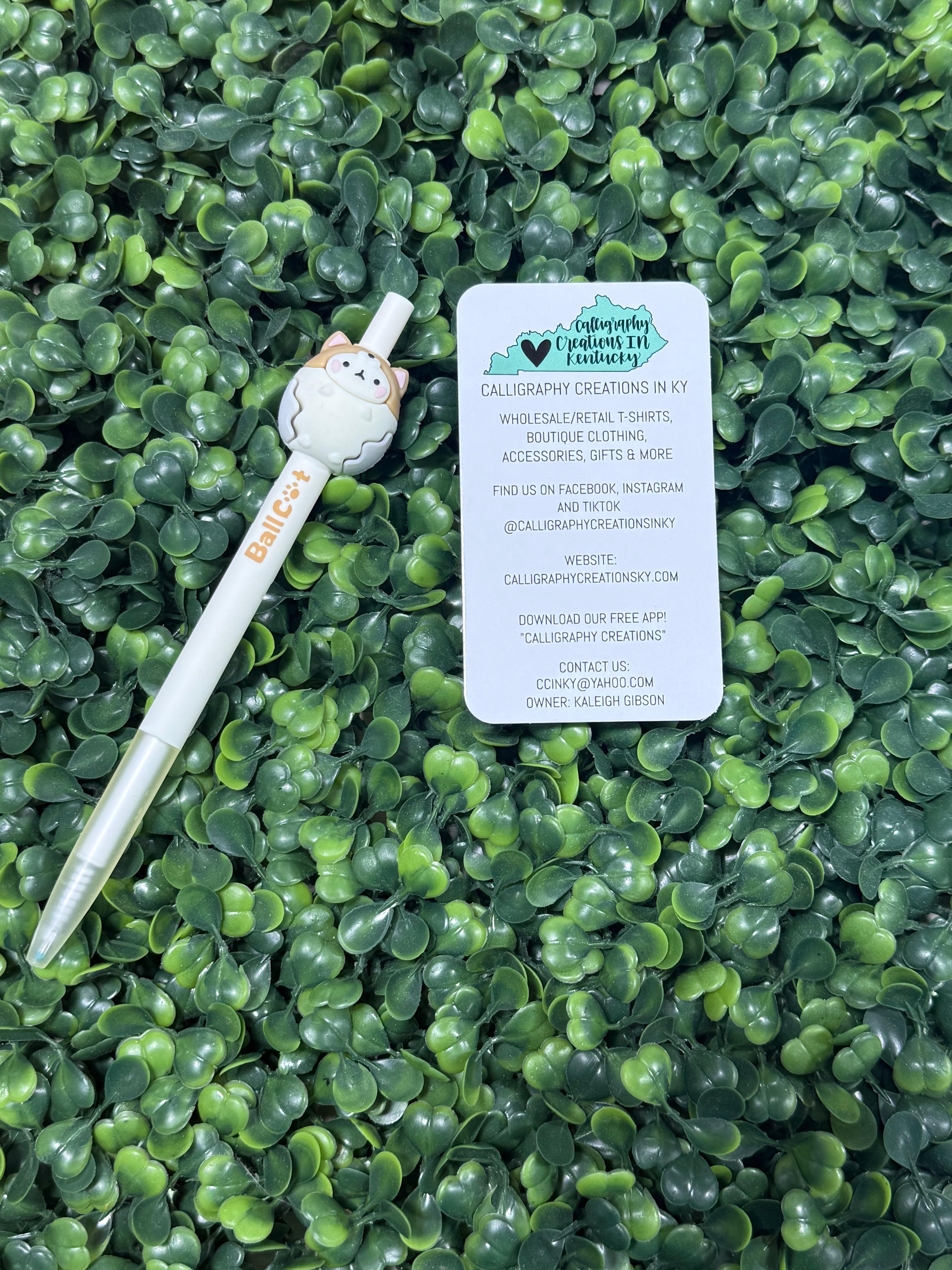 White pen with a cat-shaped top on green leafy background