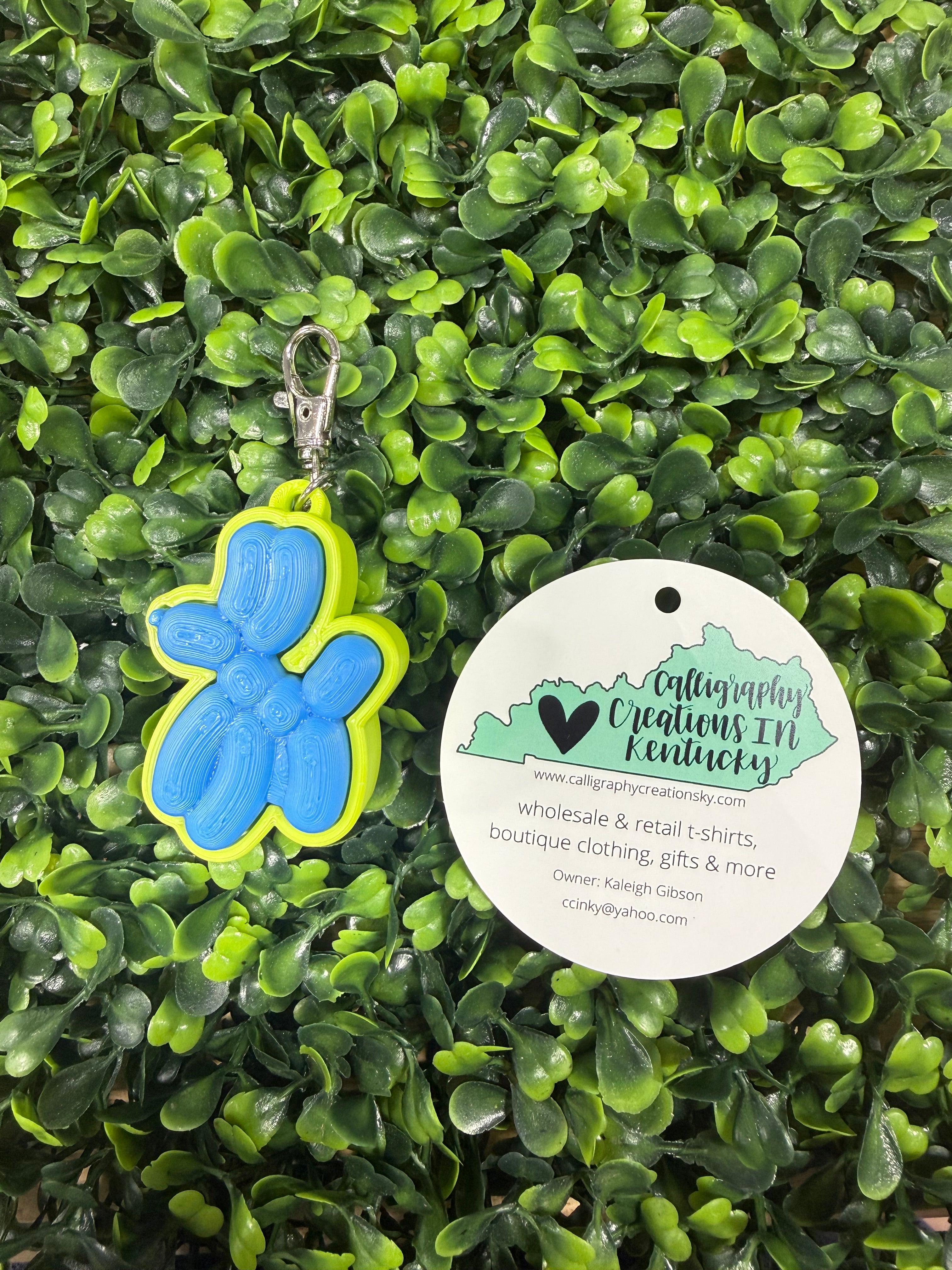 Balloon dog keychain on a green leafy background