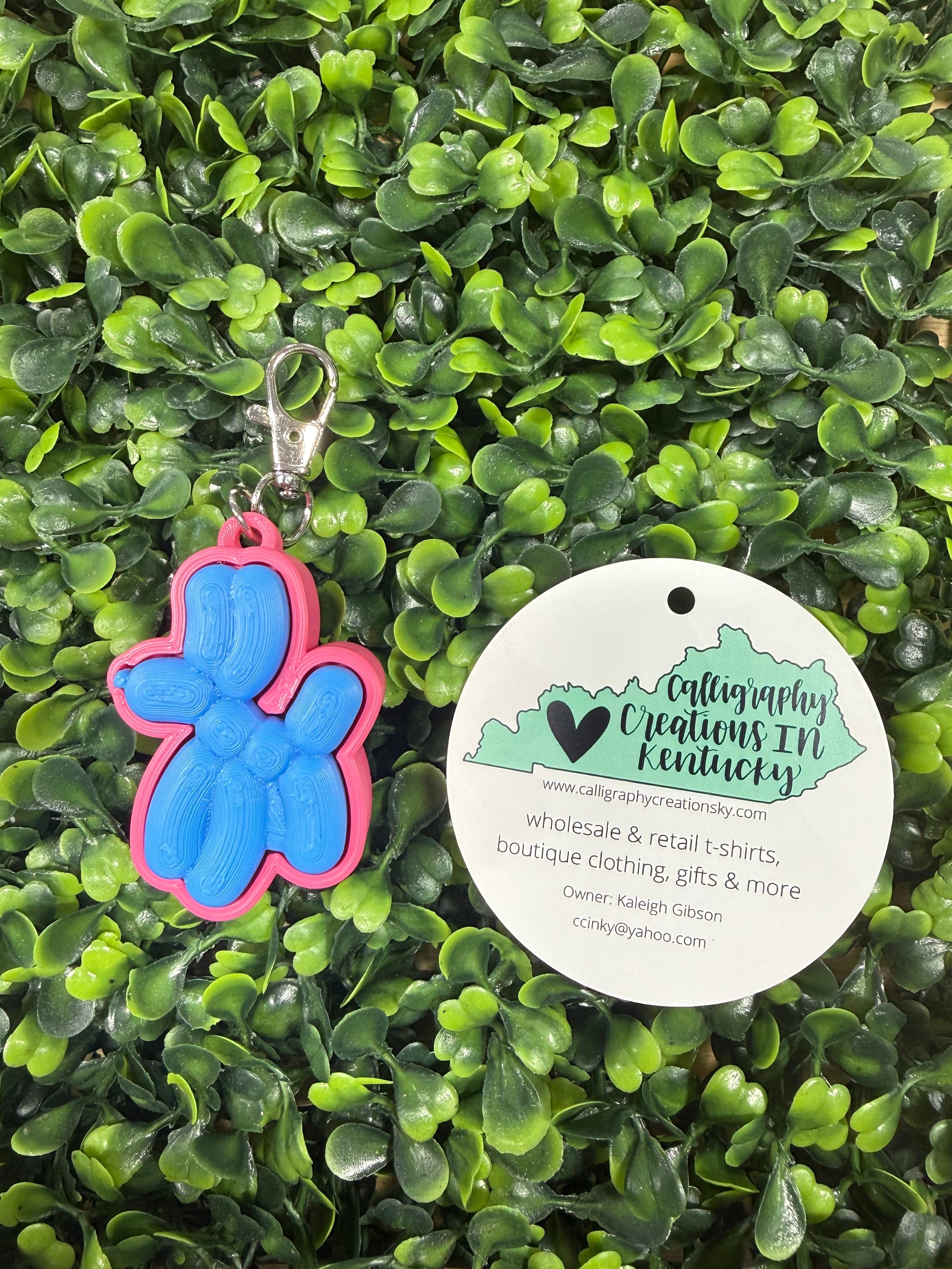 Balloon dog keychain on a leafy green background