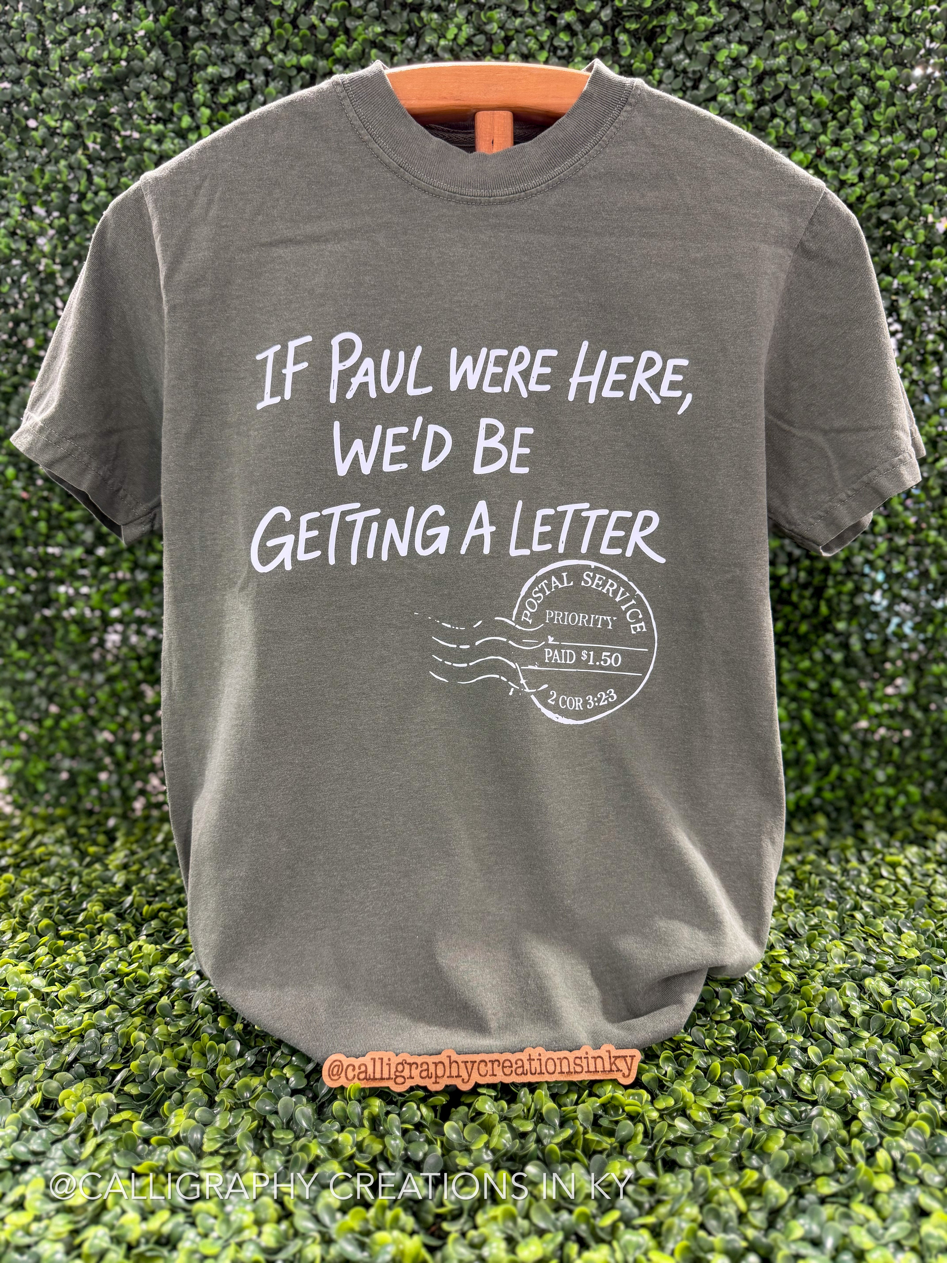 Moss Green tee with text that says “If Paul were here we’d be getting a letter”