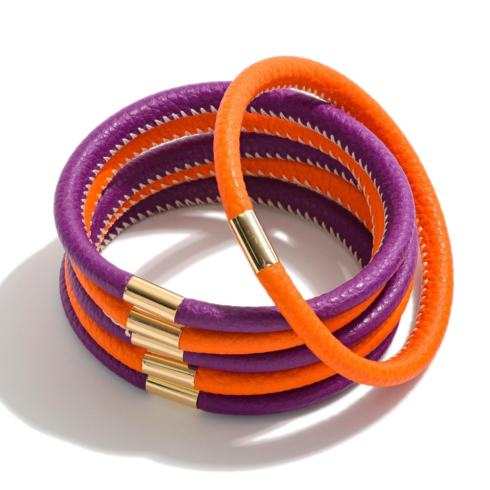 A stack of multi-strand wrap bracelets featuring alternating purple and orange textured bands, accented with polished gold metal end caps, set against a clean white background.