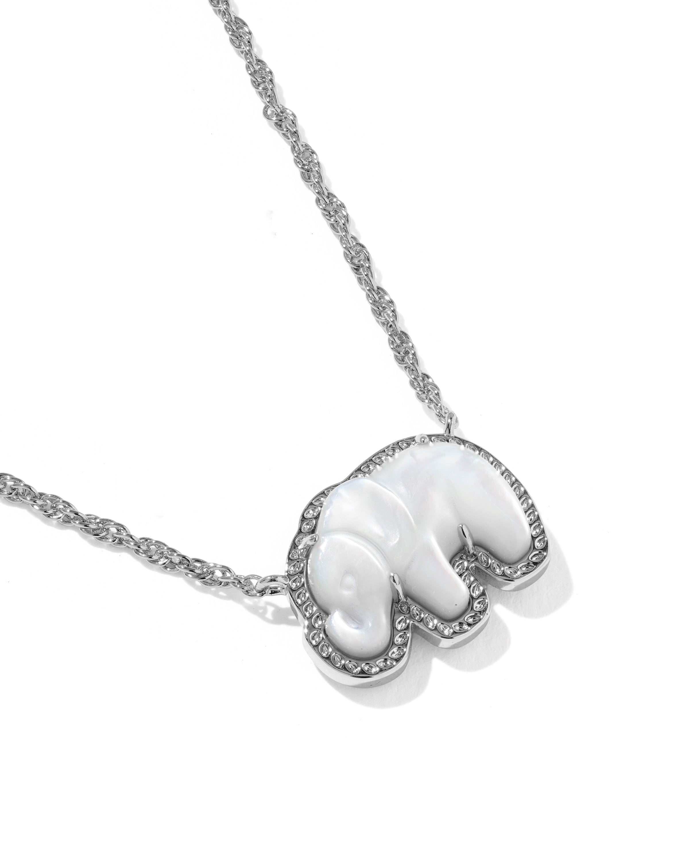 A silver-toned necklace featuring a heart-shaped pendant with a white mother-of-pearl elephant figure, accented with small clear stones along the border, set against a plain white background.