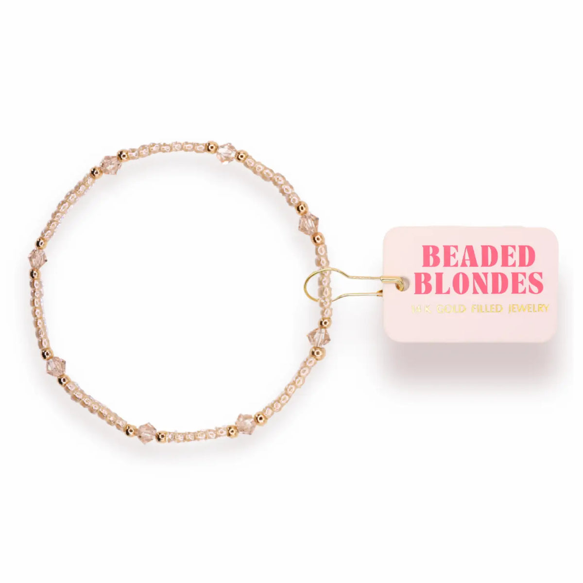 A delicate beaded bracelet in pale pink and gold, shown on a white background with its pink retail tag that reads 'BEADED BLONDES'.