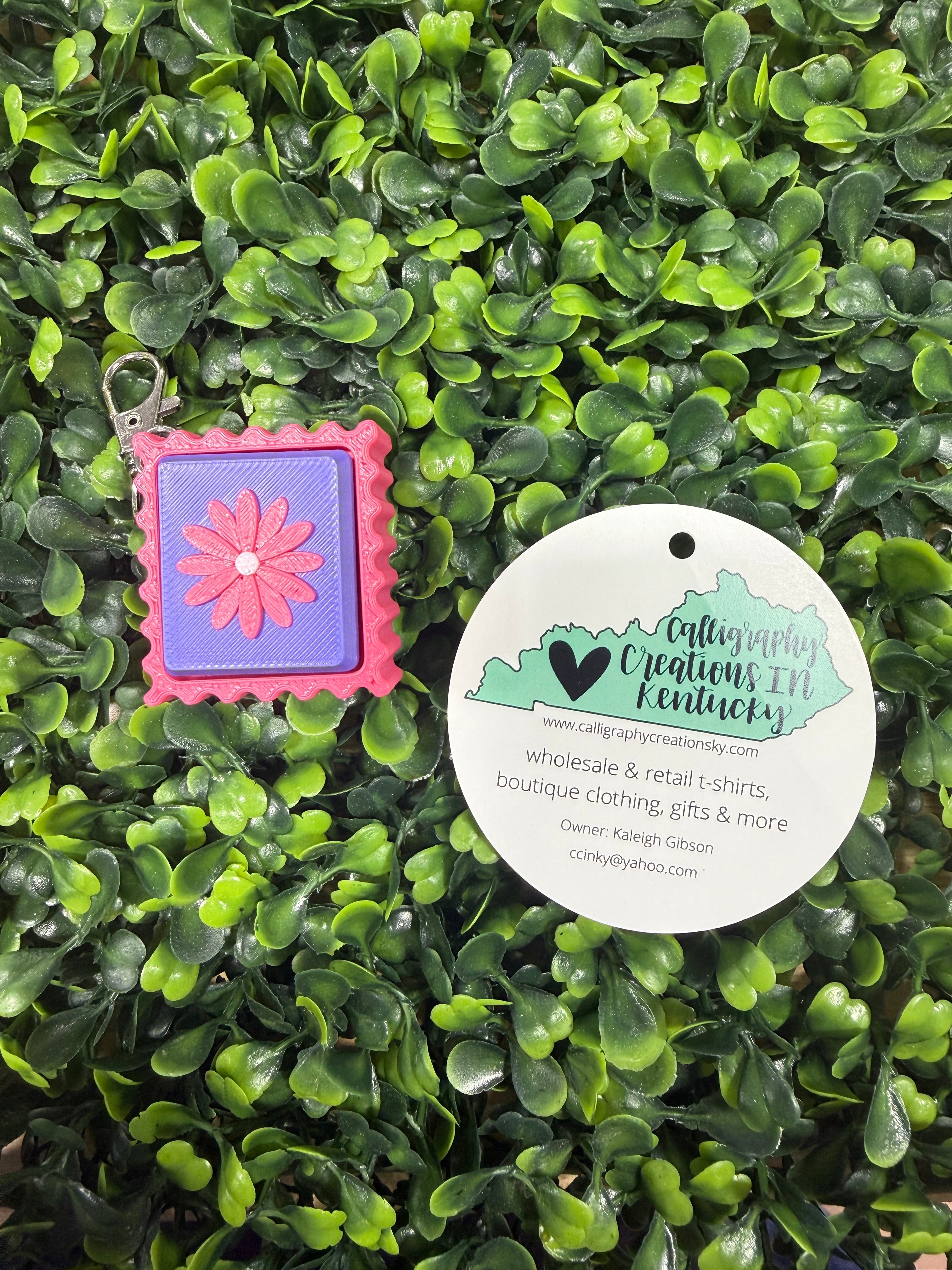 Flower stamp keychain on a green leafy background