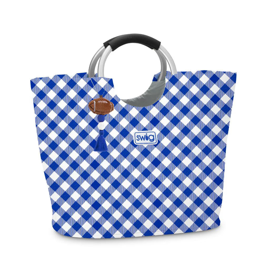 A blue and white gingham tote bag with a black handle and silver metal accents, featuring a small brown football charm and a white Swig brand patch.