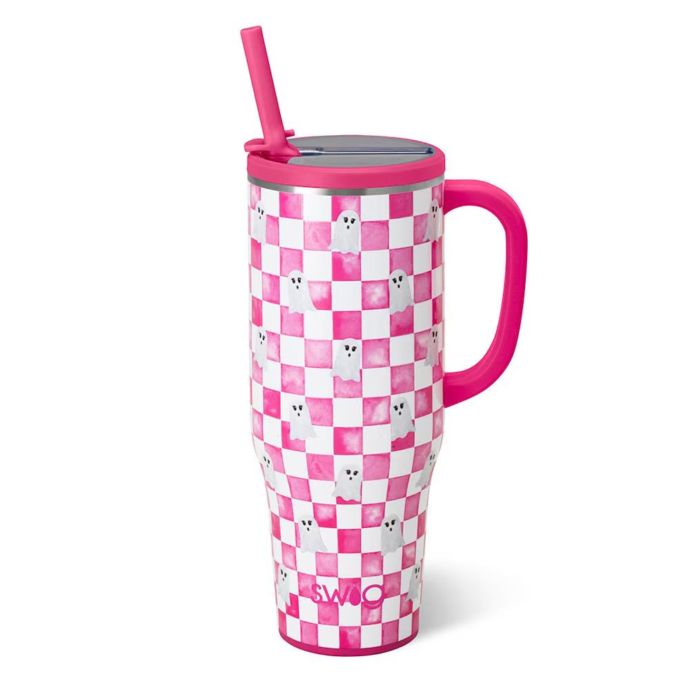 A pink and white checkered insulated tumbler with a handle, lid, and straw, decorated with small ghost illustrations and the SWIG logo near the bottom.