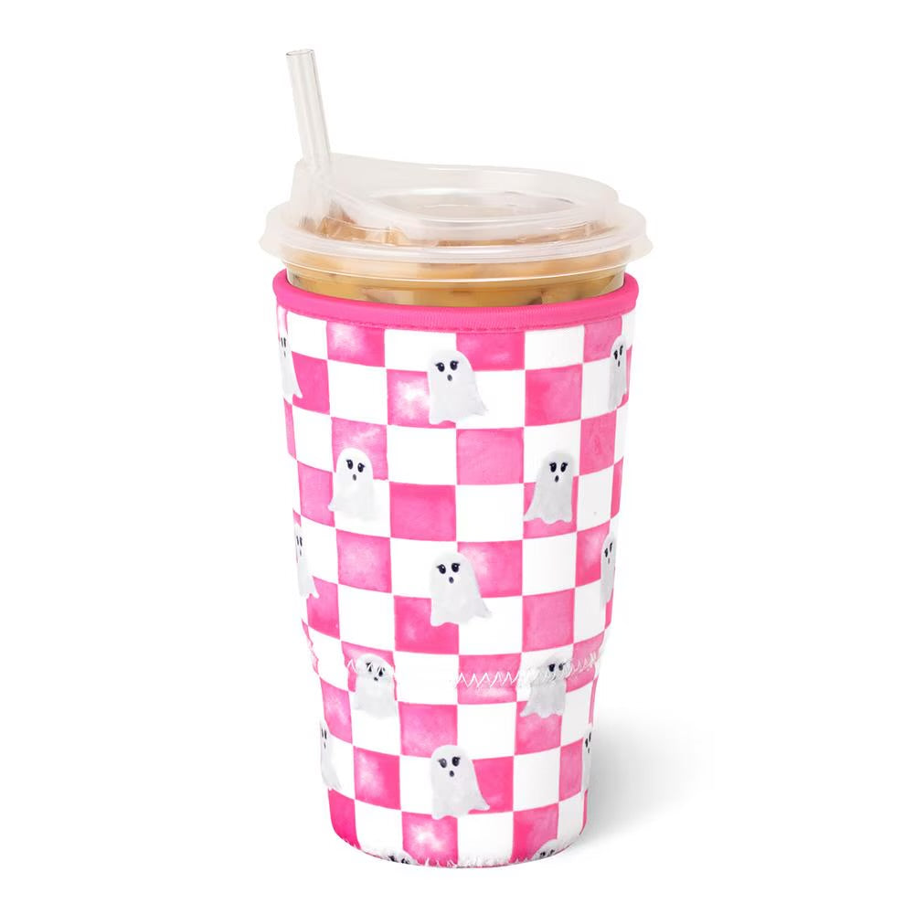 A pink and white checkered insulated tumbler sleeve with small white ghost illustrations, shown on a clear-lidded plastic cup with a straw against a white background.
