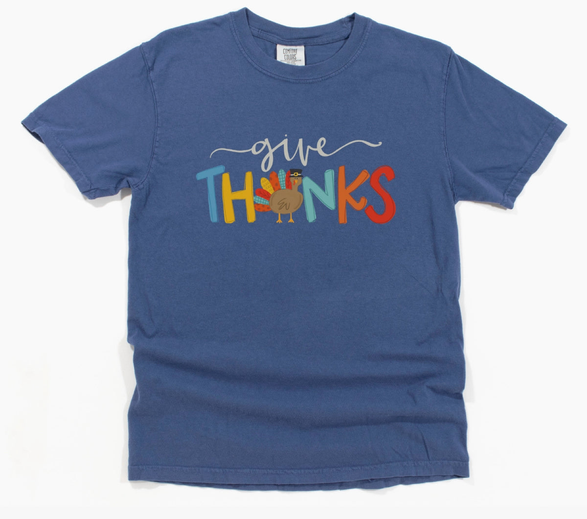 A blue short-sleeve crewneck t-shirt featuring a colorful graphic on the front that reads 'give THANKS' with a small Santa Claus figure inside the letter 'I'.