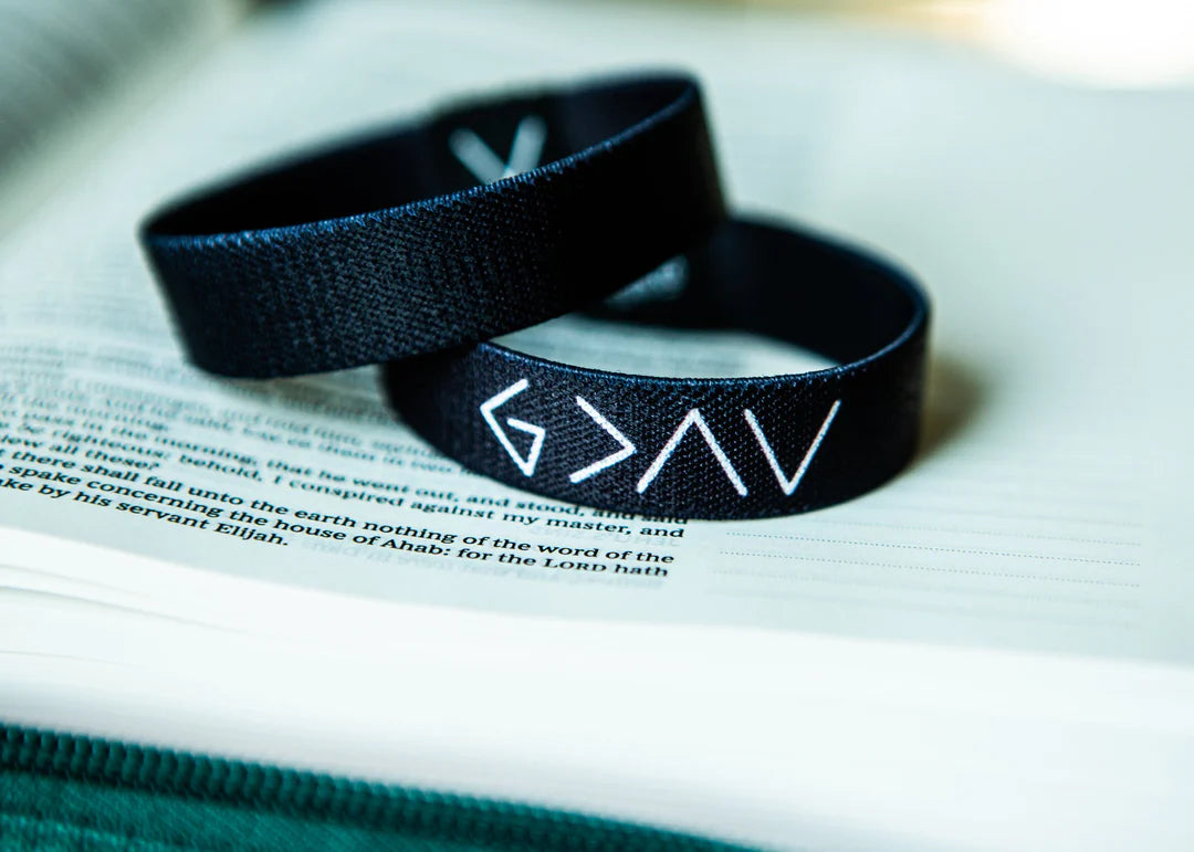 Two black fabric wristbands with white symbols resting on an open book.
