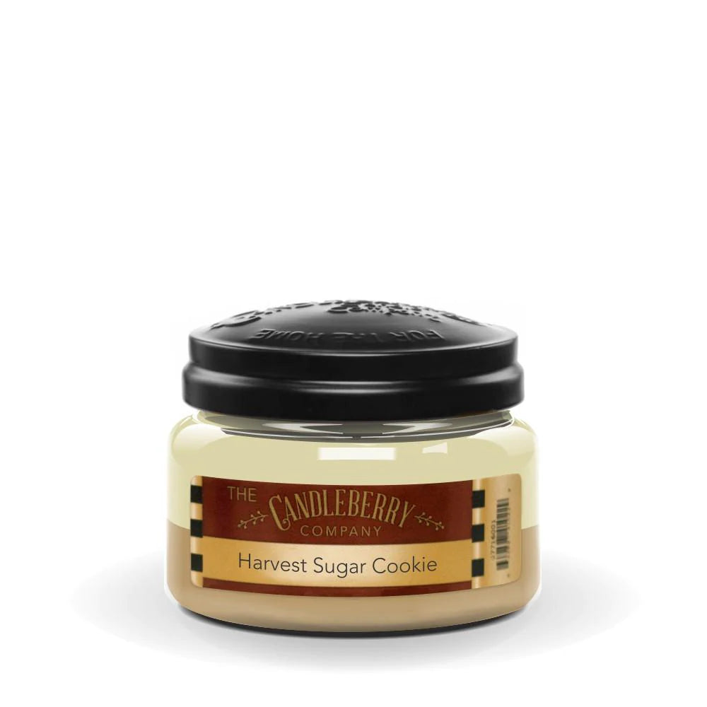 A small jar candle with a black lid, labeled 'Harvest Sugar Cookie', indicating a scent of freshly baked sugar cookies.