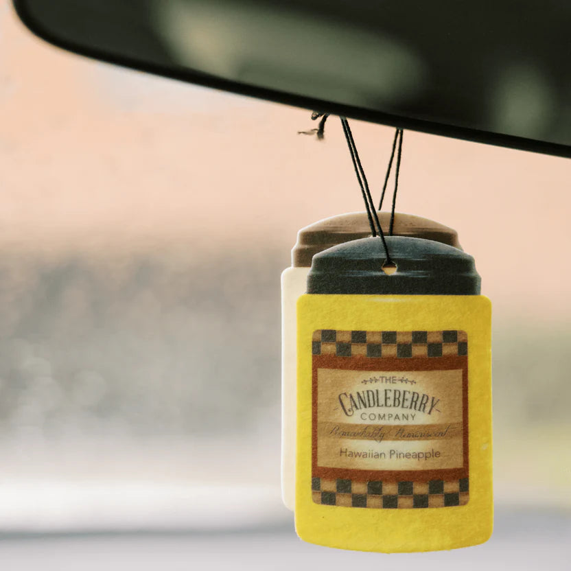 A hanging car air freshener with a yellow label that reads 'Candleberry Hawaiian Pineapple'.