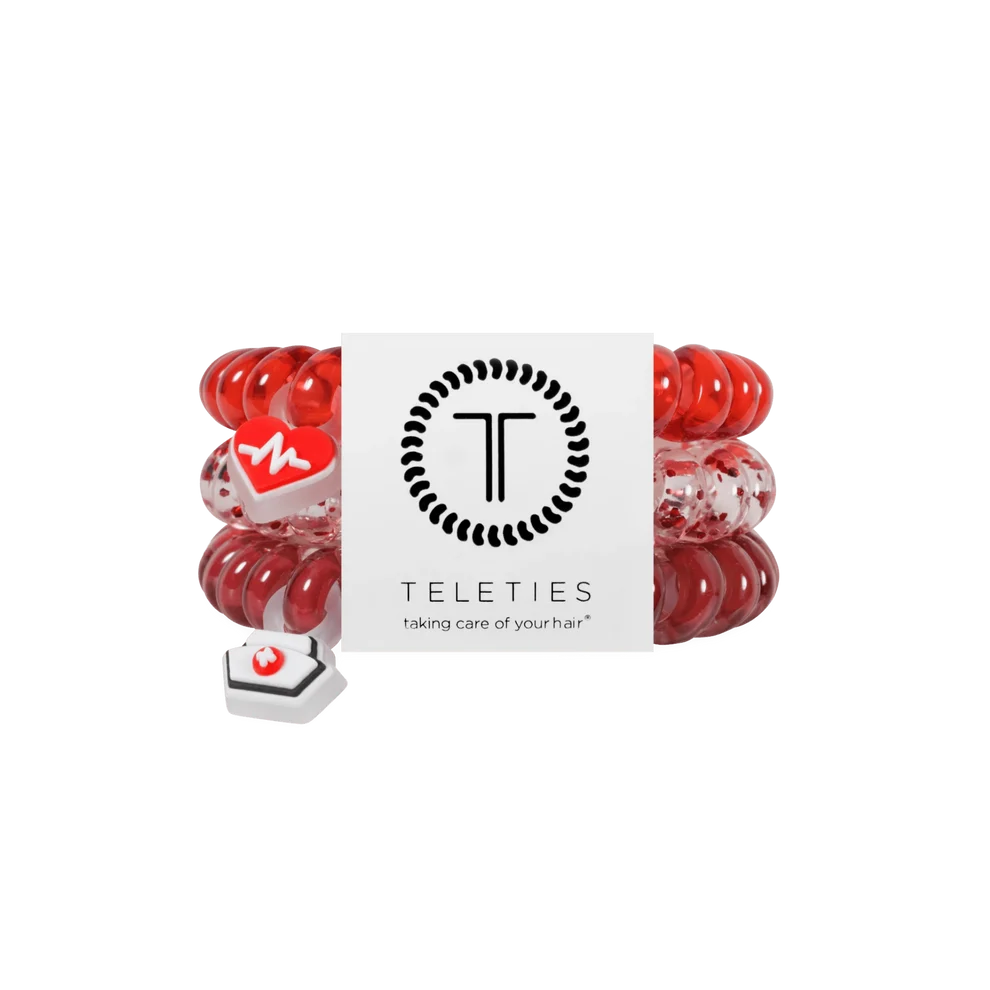 Teleties red and white elastic hair ties with a white branded paper band and a small white heart-shaped accessory, shown on a plain white background.