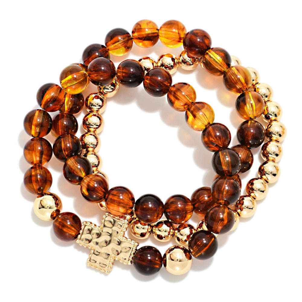 Two beaded bracelets with gold accents and a cross charm on a white background