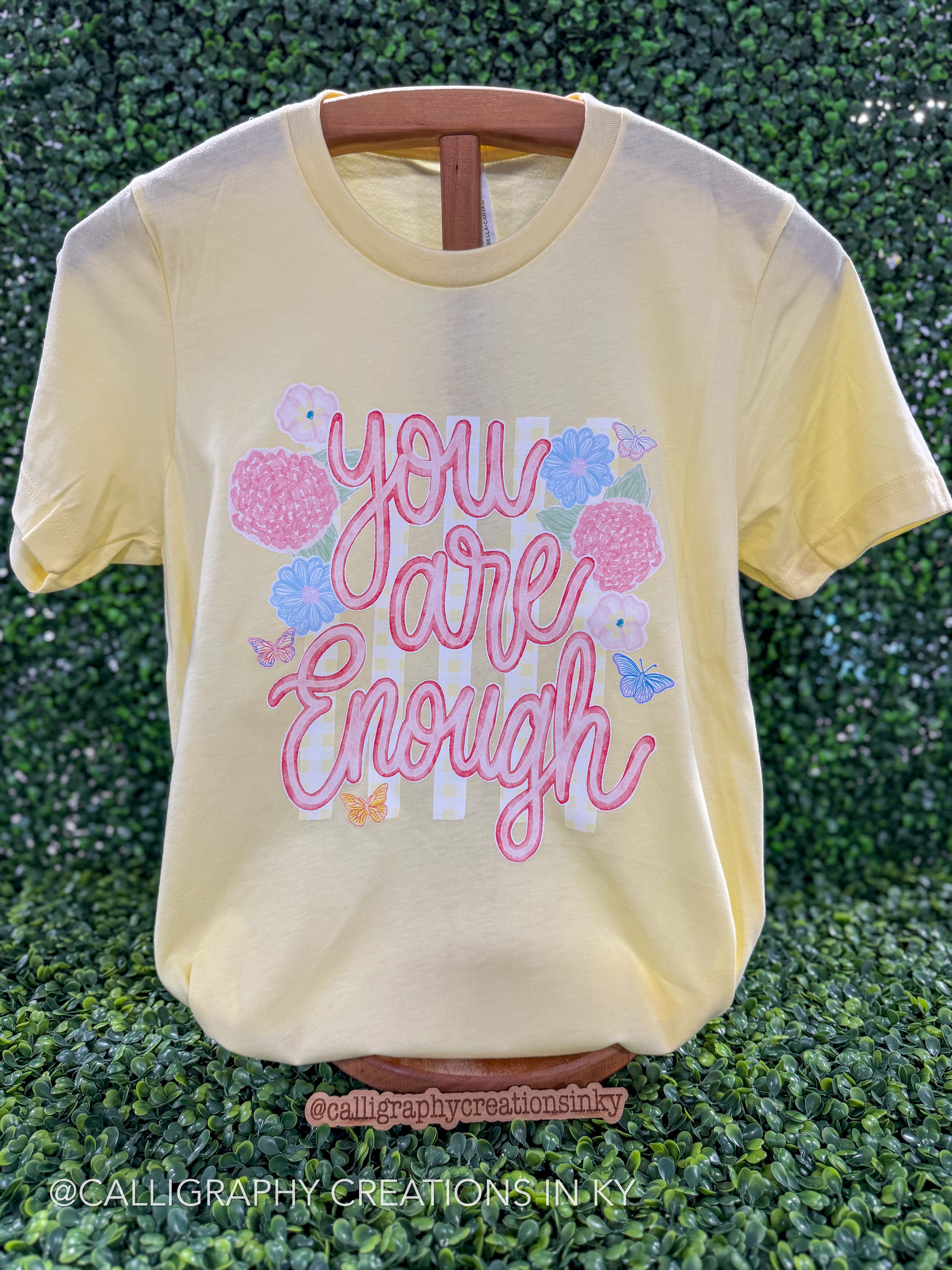 Yellow colored tee with text that says “you are enough”