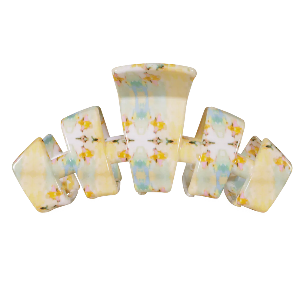 A vintage-style plastic claw hair clip with a marbled pattern of pale yellow, white, light blue, and small yellow floral accents, shown on a plain white background.