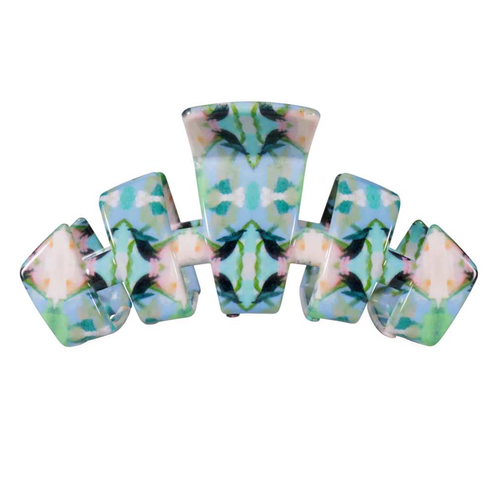 A hair claw clip featuring a symmetrical, kaleidoscopic tie-dye pattern in shades of light blue, mint green, teal, and cream.