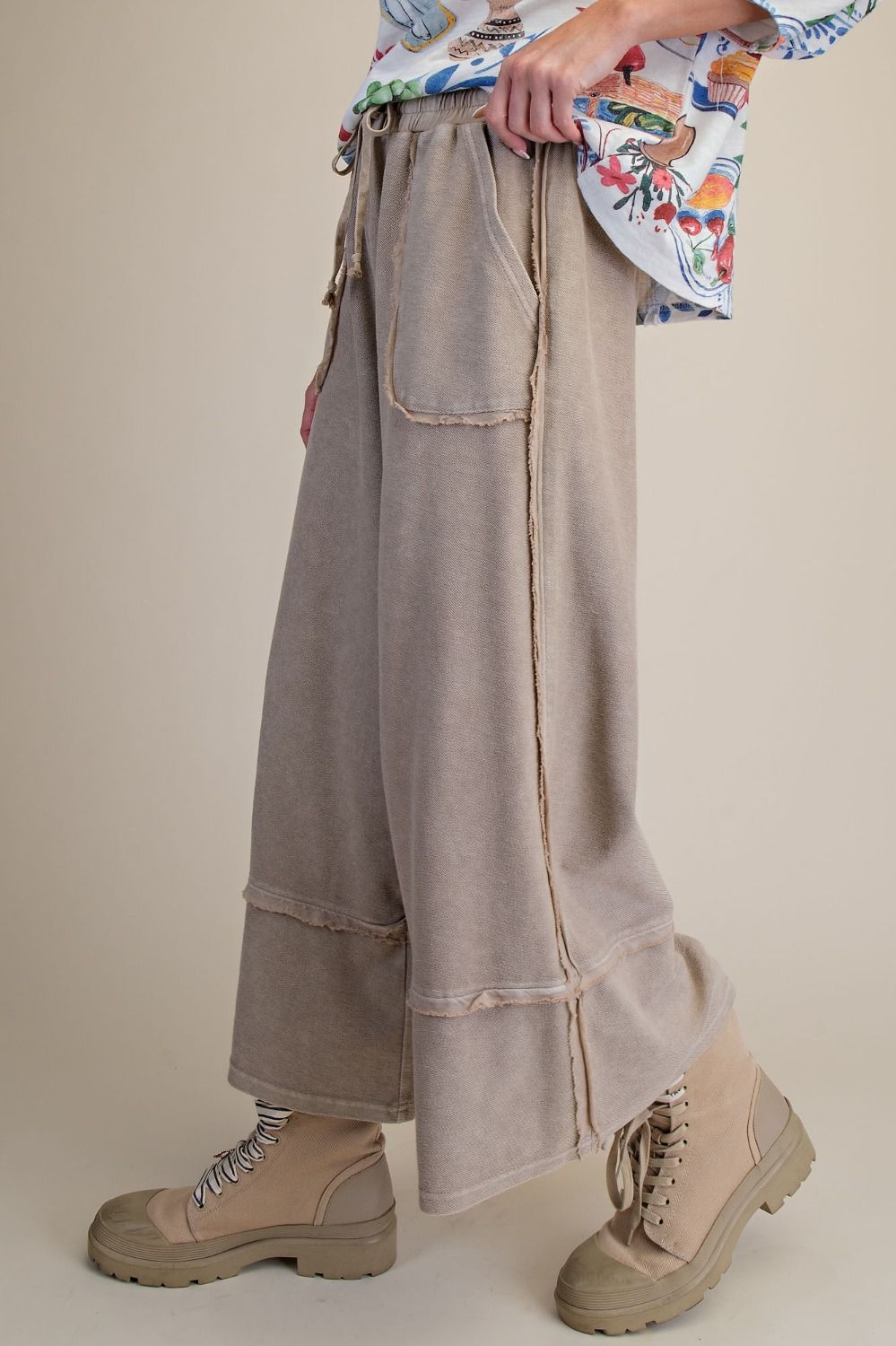 Beige wide-leg pants worn with a colorful shirt and beige boots on a neutral background