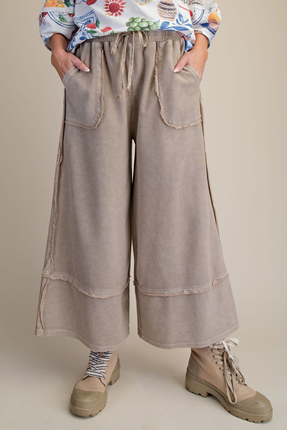 Person wearing beige wide-leg pants with a plain background