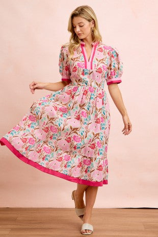 Woman wearing a floral dress with pink trim on a pink background