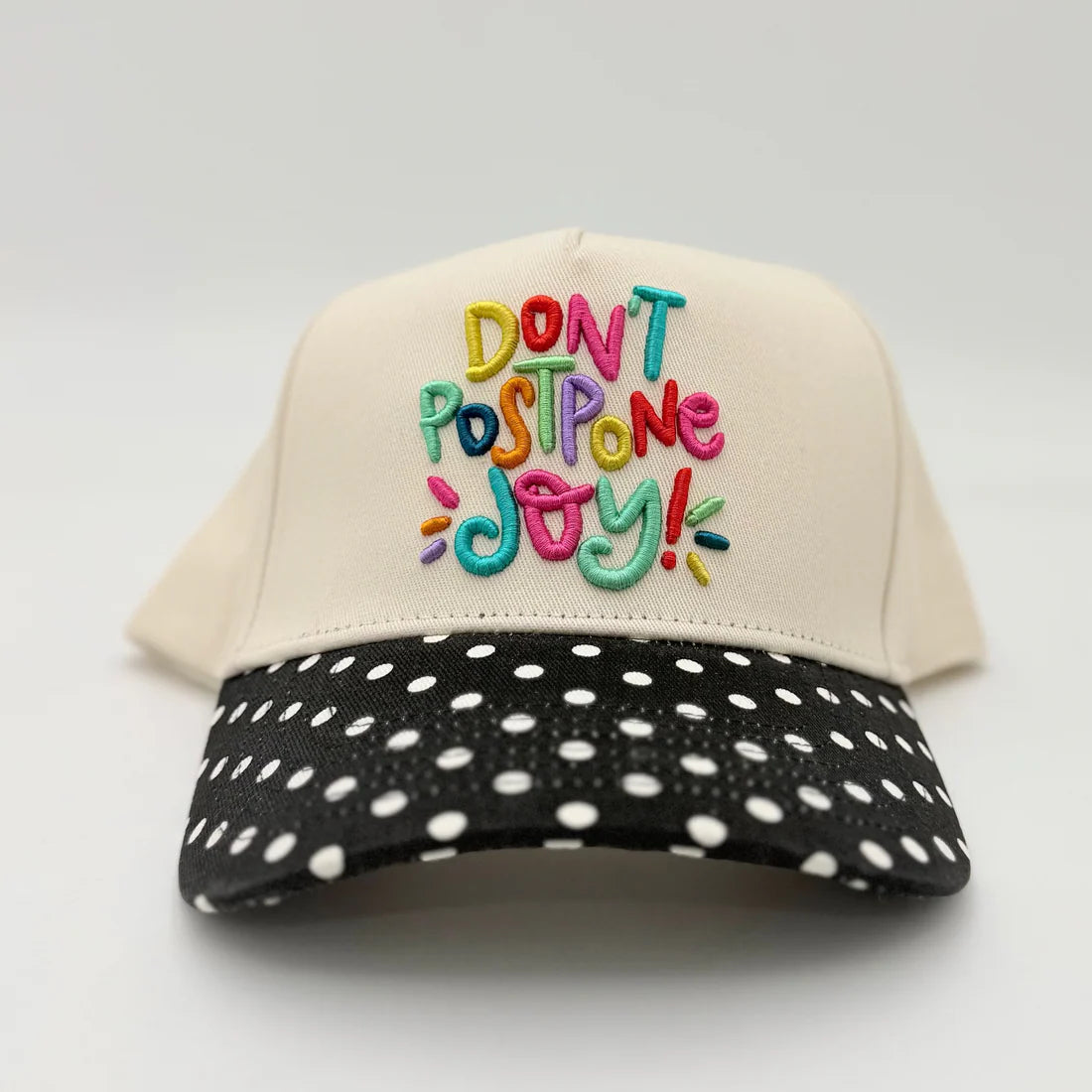 Cap with colorful text 'Don't Postpone Joy!' on a white background