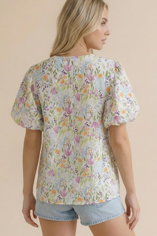 Woman wearing a floral blouse with puff sleeves on a beige background