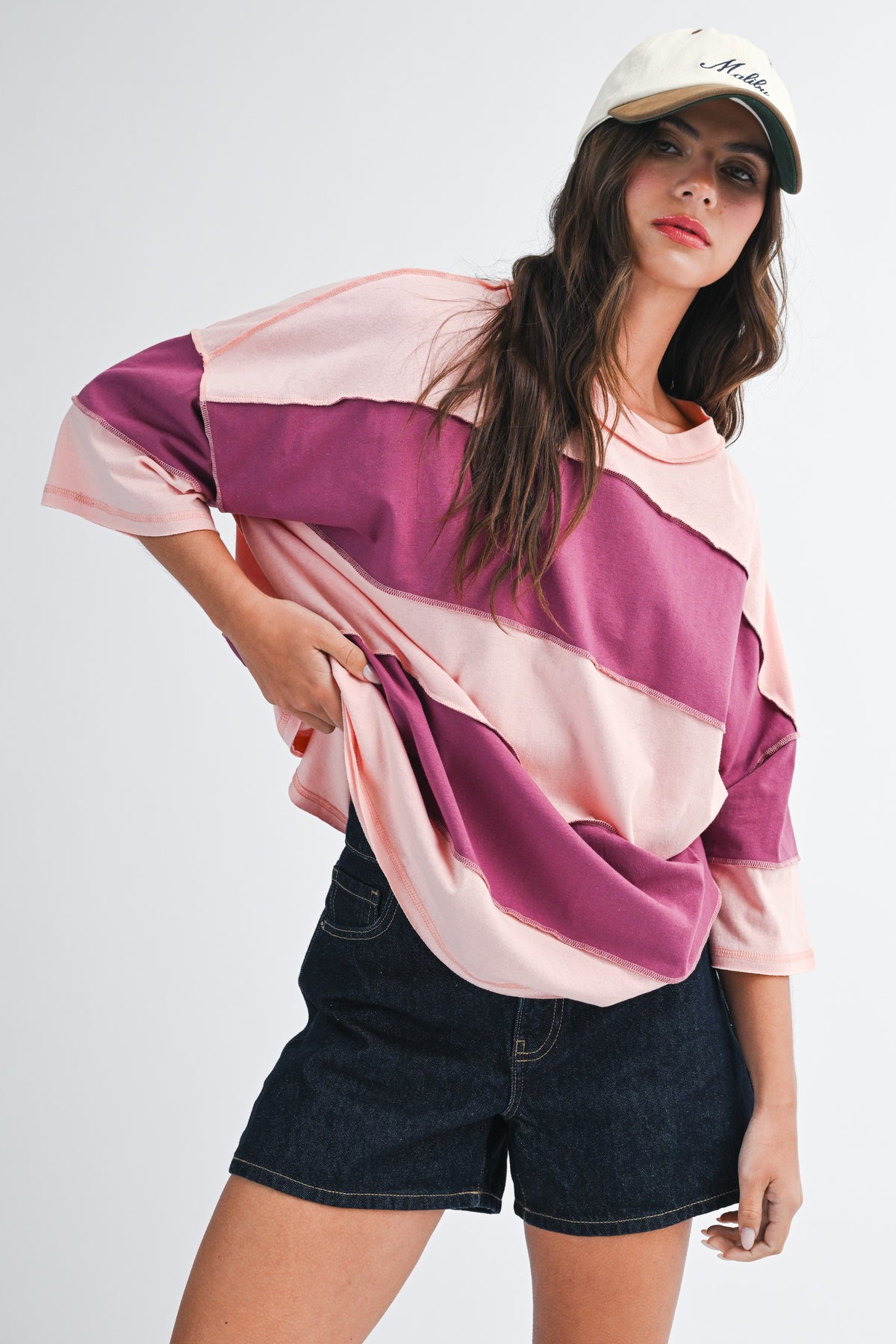 Woman wearing a pink and purple striped shirt with denim shorts on a white background