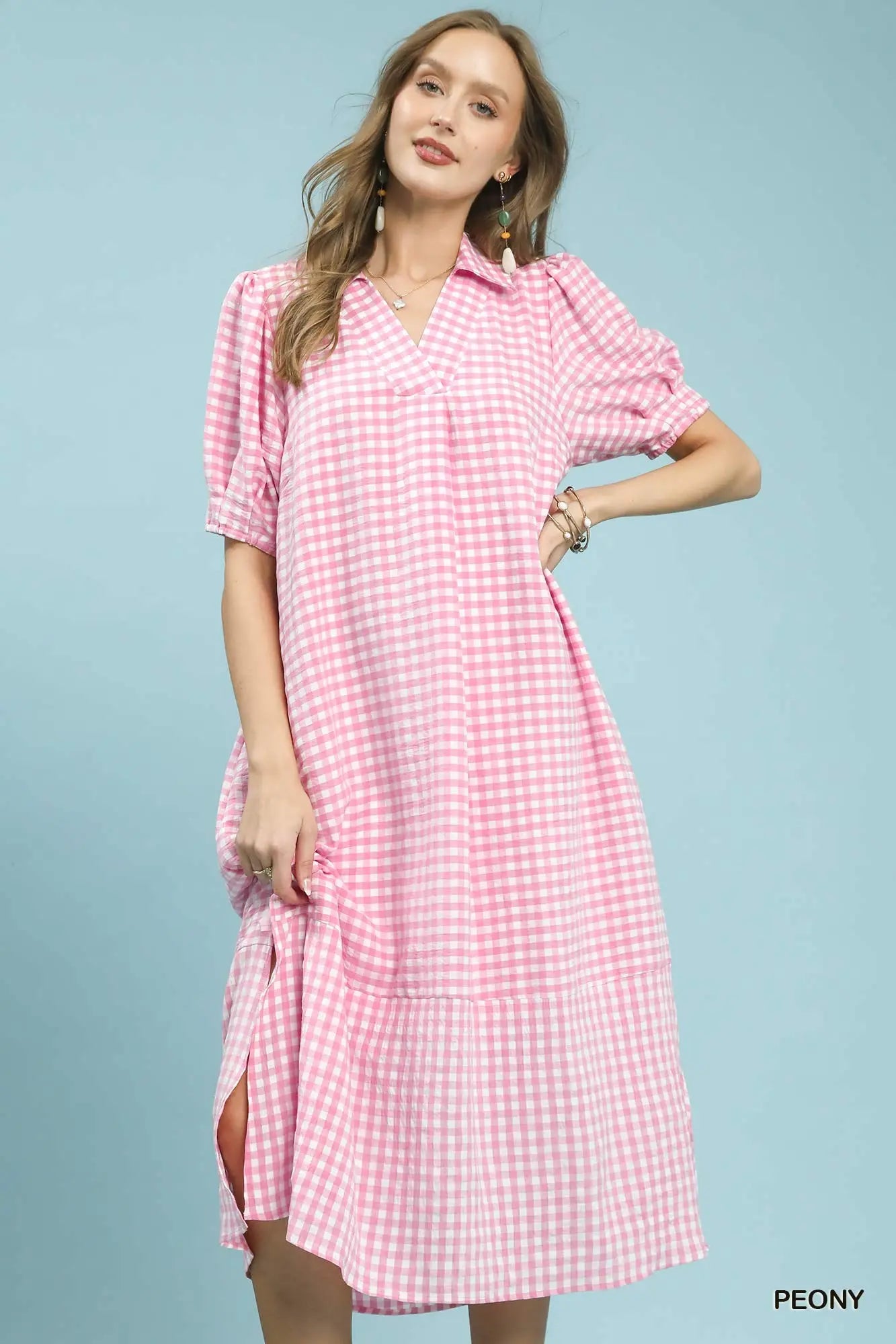 Woman wearing a pink checkered dress against a light blue background