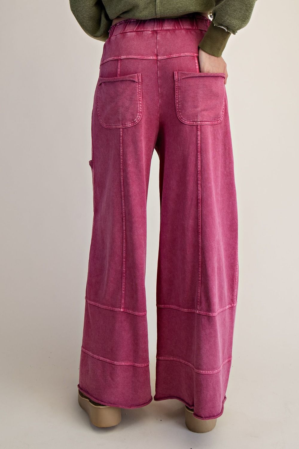 Back of a person wearing berry colored pants with a neutral background