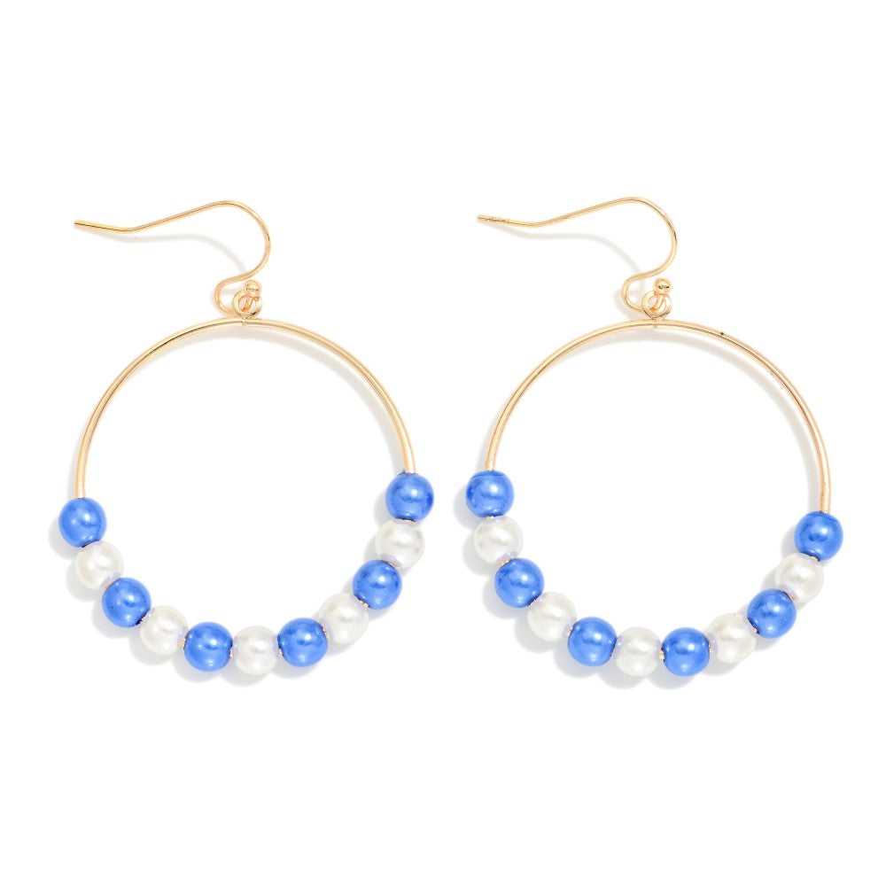 A pair of gold hoop earrings decorated with alternating blue and white pearl-like beads along the bottom curve, shown on a plain white background.